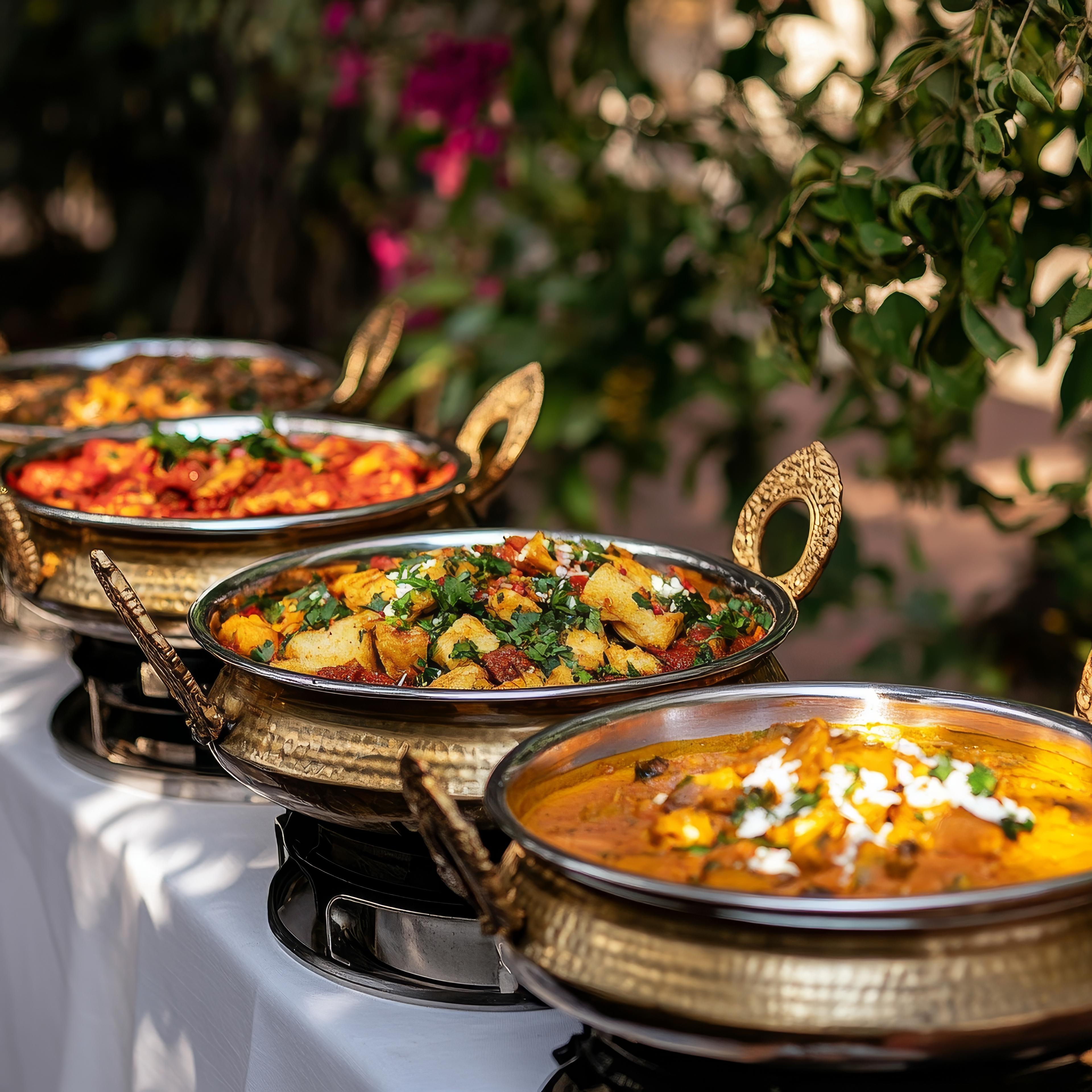 Traditional Indian dishes served in ornate brass bowls at an outdoor event